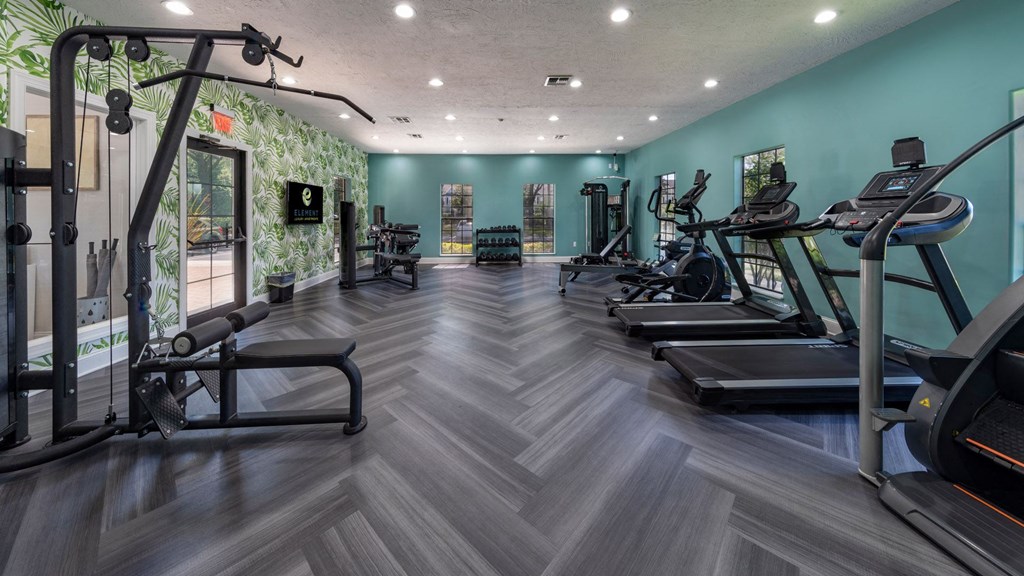 a gym with cardio machines and weights on a wooden floor