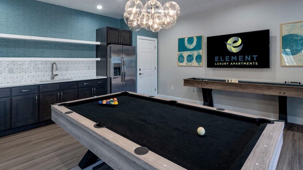 a billiards table in a game room with a kitchen