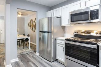 a kitchen with white cabinets and stainless steel appliances at Station JTown, Louisville Kentucky