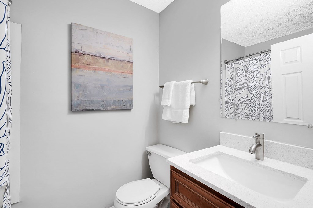 a bathroom with a toilet sink and mirror at Stonewater Apartments, Kentucky