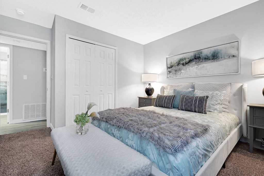 a bedroom with a bed and a nightstand with a vase of flowers on it at Stonewater Apartments, Louisville, KY