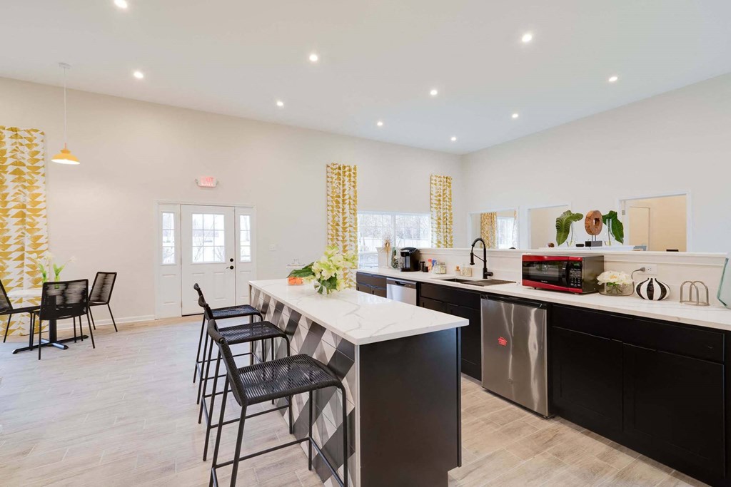 a kitchen with a long counter and black and white chairs at Station JTown, Kentucky, 40299