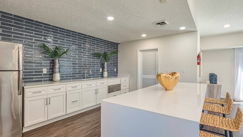 A kitchen with white cabinets and a blue backsplash.