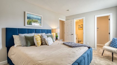 A bedroom with a large bed and a painting on the wall.