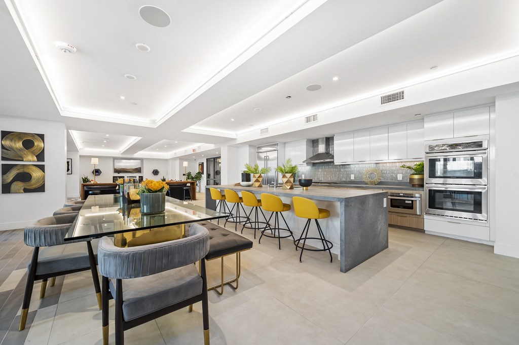 the kitchen has a large island with yellow chairs and stainless steel appliances