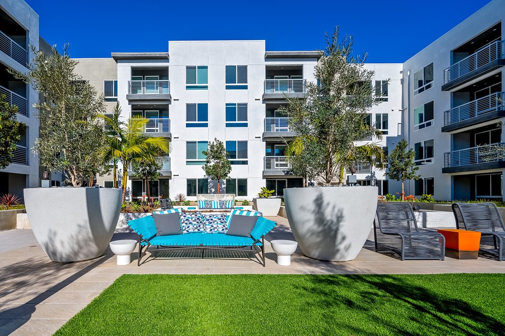 an outdoor lounge area with a couch in front of an apartment building