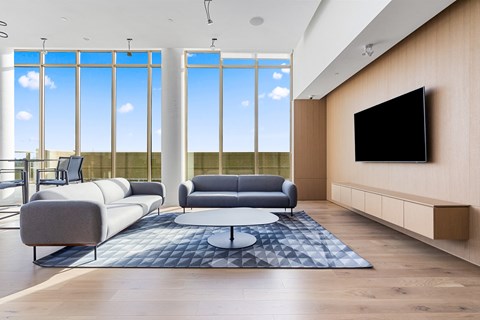 A modern living room with a large window and a flat screen TV mounted on the wall.