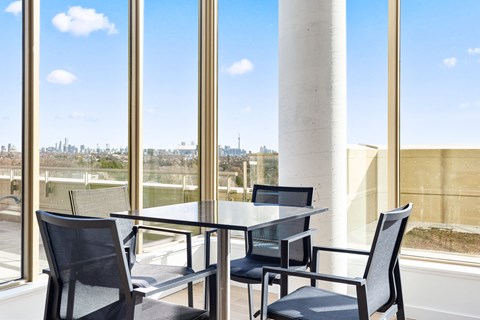 A table with four chairs is in front of a large window.