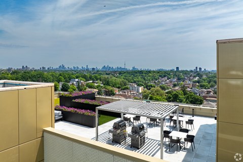 A rooftop patio with a table and chairs overlooking a city skyline.