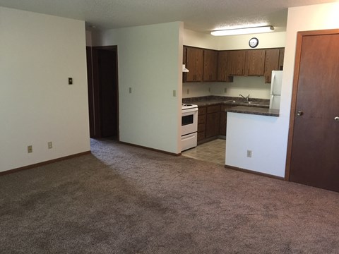 an empty living room with a kitchen in it