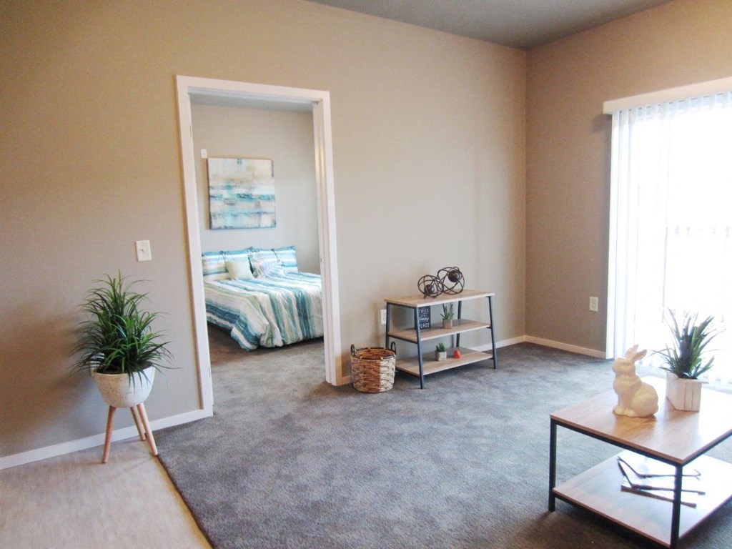 an empty living room with a bedroom in the background