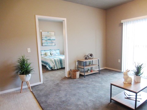 an empty living room with a bedroom in the background