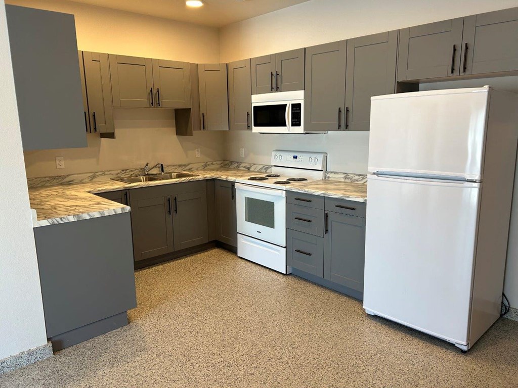 a kitchen with white appliances and gray cabinets