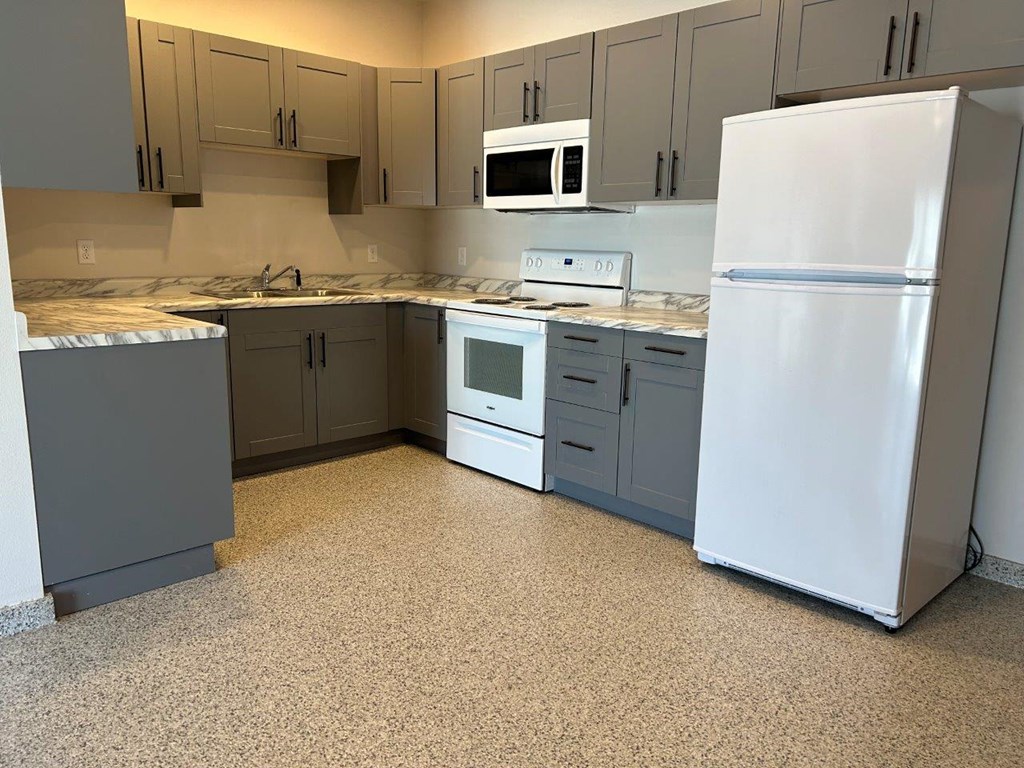 a kitchen with white appliances and gray cabinets