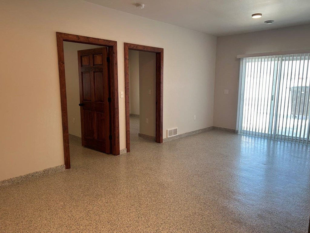 an empty living room with a window and a door