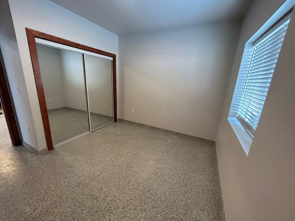 a bedroom with a mirrored closet and a window