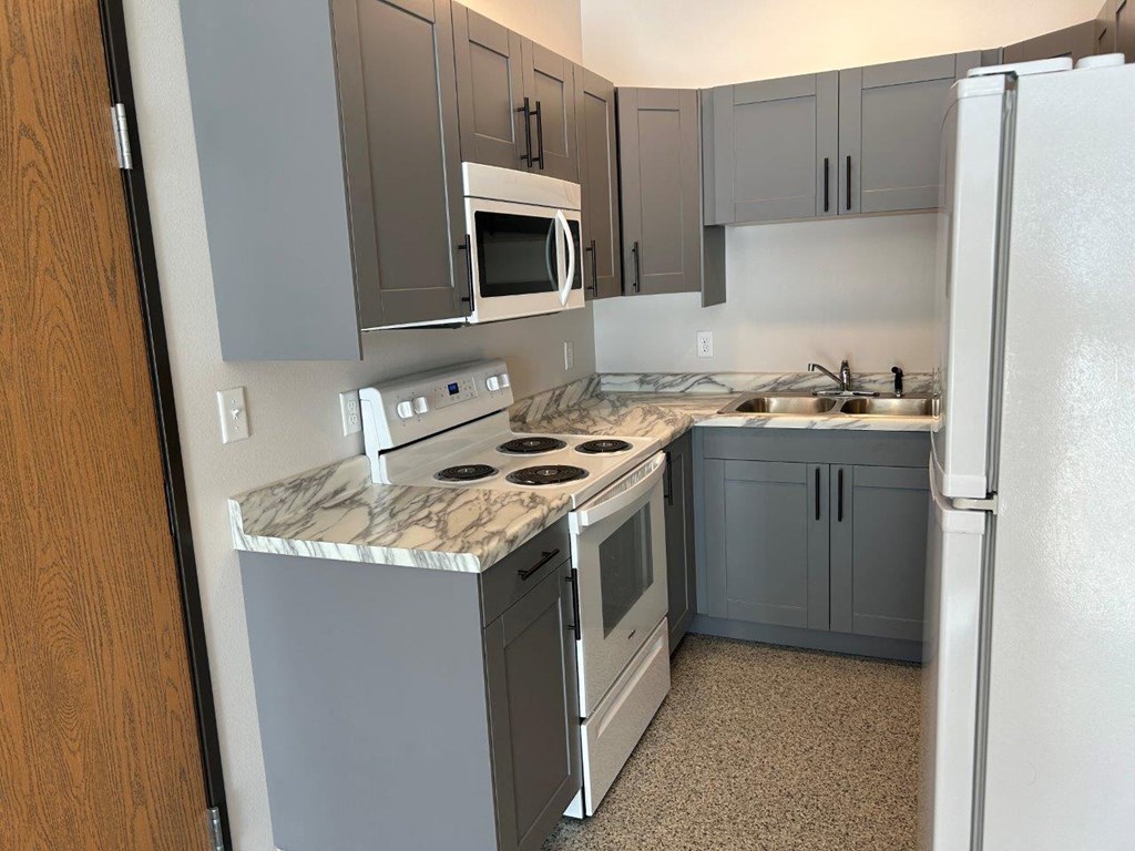 a kitchen with white appliances and gray cabinets