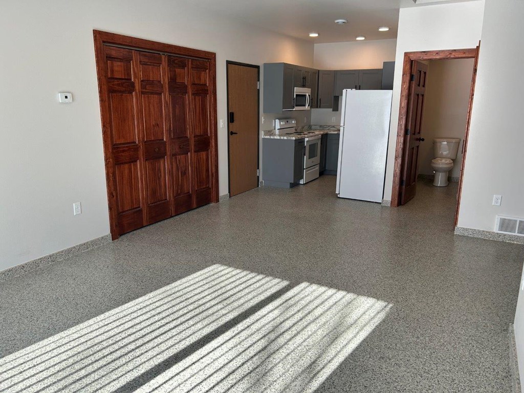 a kitchen and a living room with a refrigerator and a sink
