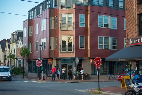 people standing outside of a building on a street corner