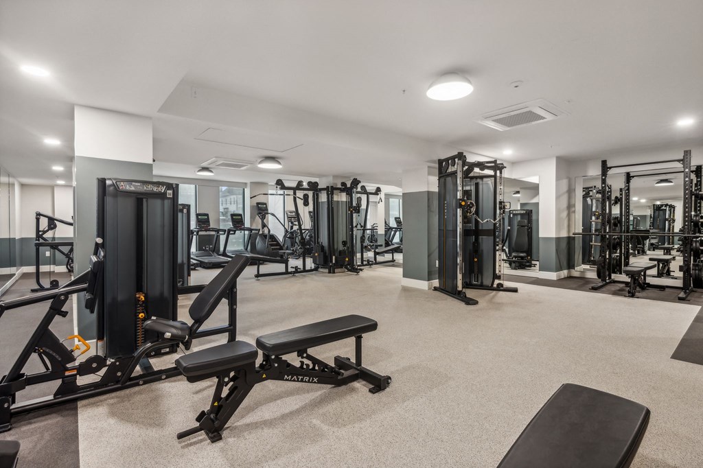 a gym with weights and cardio equipment in a building with white walls