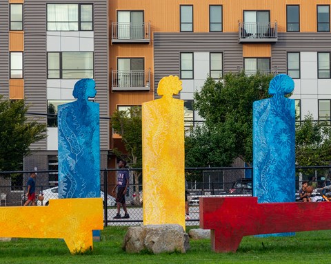 three sculptures in the grass in front of an apartment building