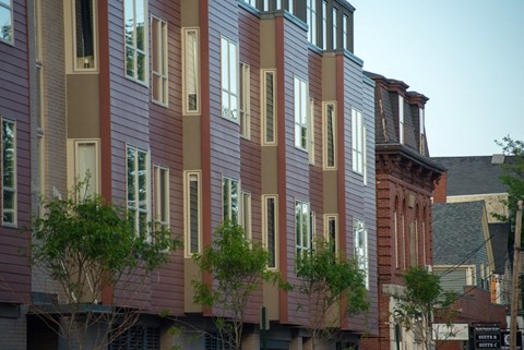 a row of houses with red and gray siding on a city street