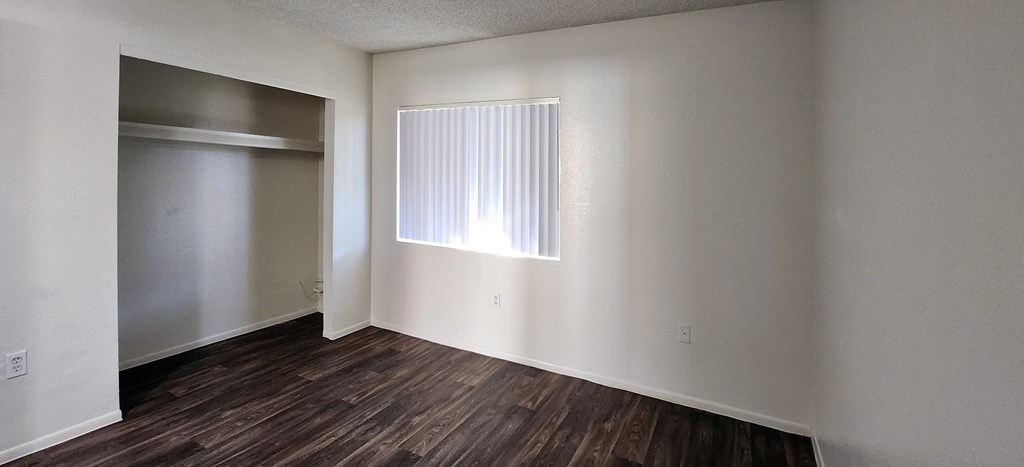 a bedroom with white walls, a window and a closet