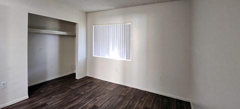a bedroom with white walls, a window and a closet