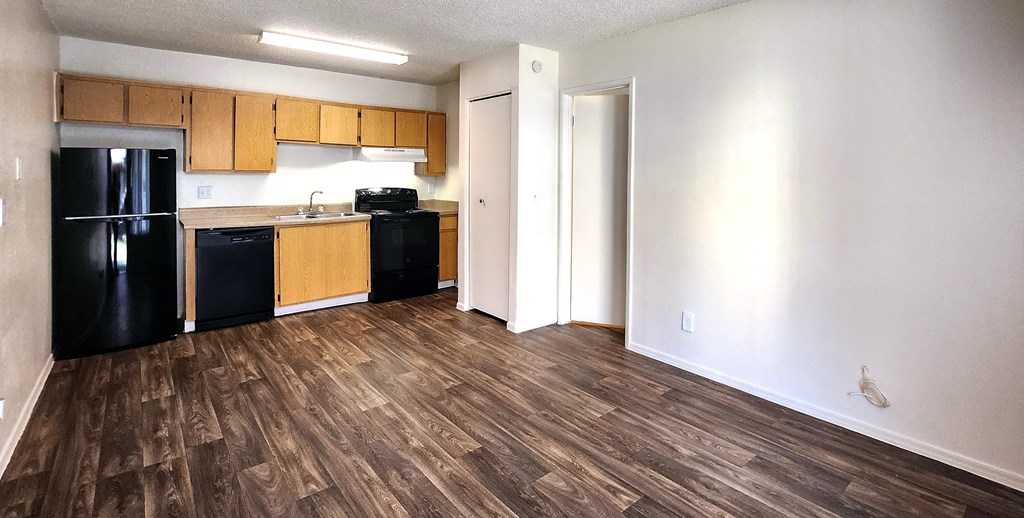 a kitchen with black appliances and wood laminate flooring