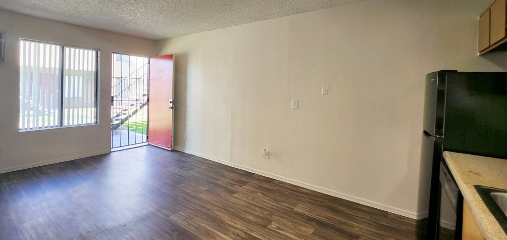 a living room, facing the main entry with a red door and window