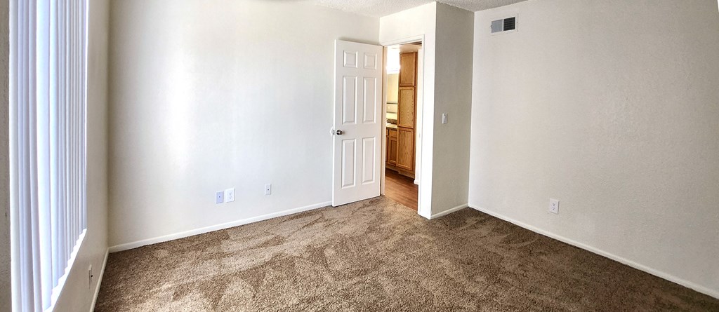 a bedroom with a carpeted floor and a door to a bathroom