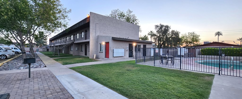 A walkway leading to a pool with a black fence and apartment building