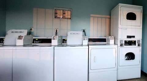 a row of washers and dryers in a community laundry room