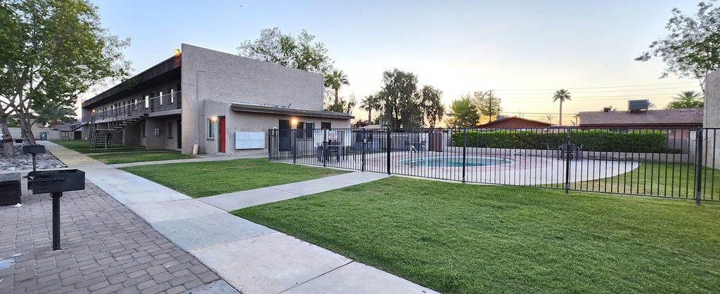 a community lawn with a pool and black metal fence and BBQ grills