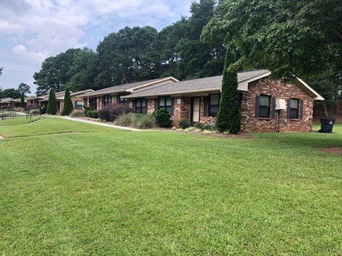a row of houses with a green lawn and trees