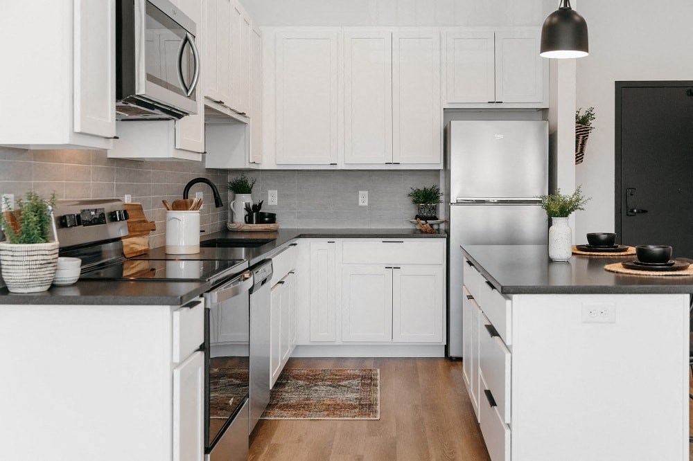 a white kitchen with black counter tops and white cabinets