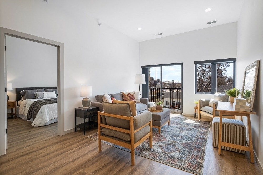 a living room with a couch and chairs and a bed in a bedroom