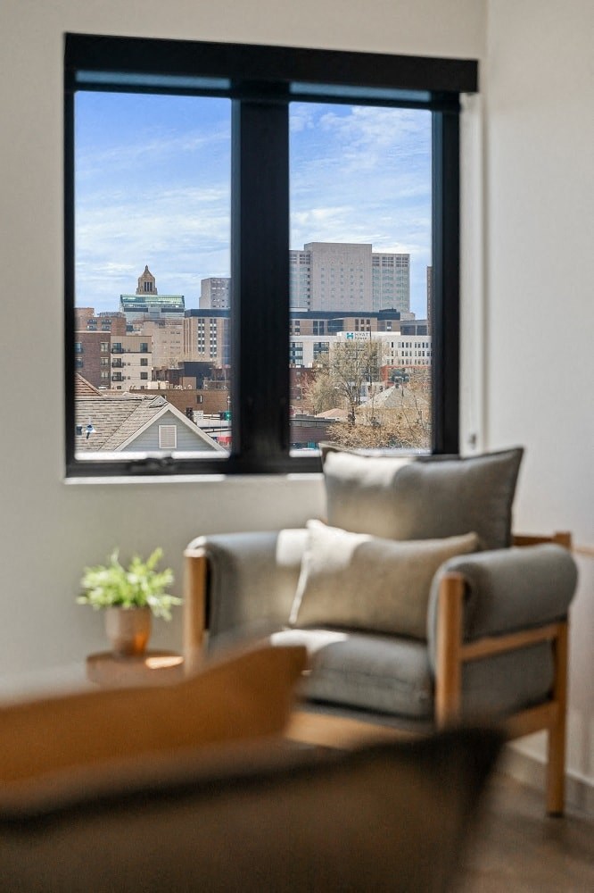 a living room with a chair and a window overlooking a city