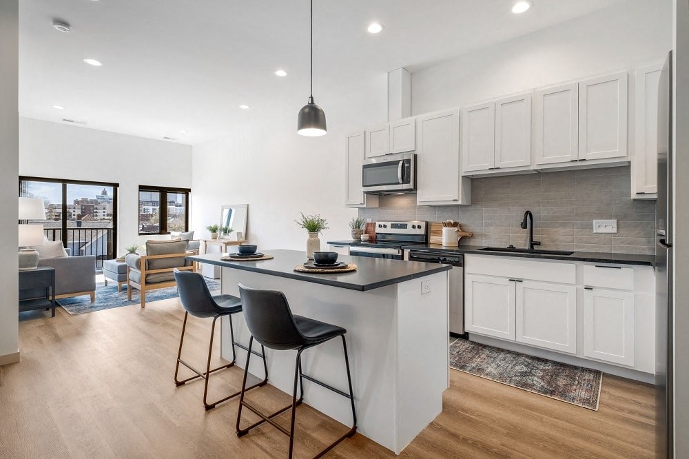 an open kitchen and living room with an island and stools