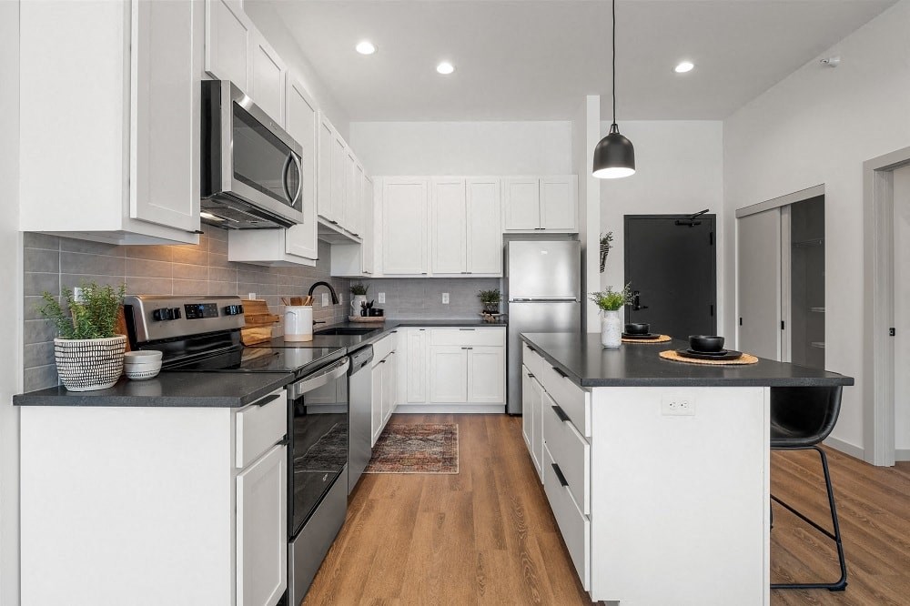 an open kitchen with black counter tops and white cabinets