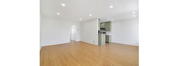 A room with wooden floors and a white wall with a cabinet and mirror.