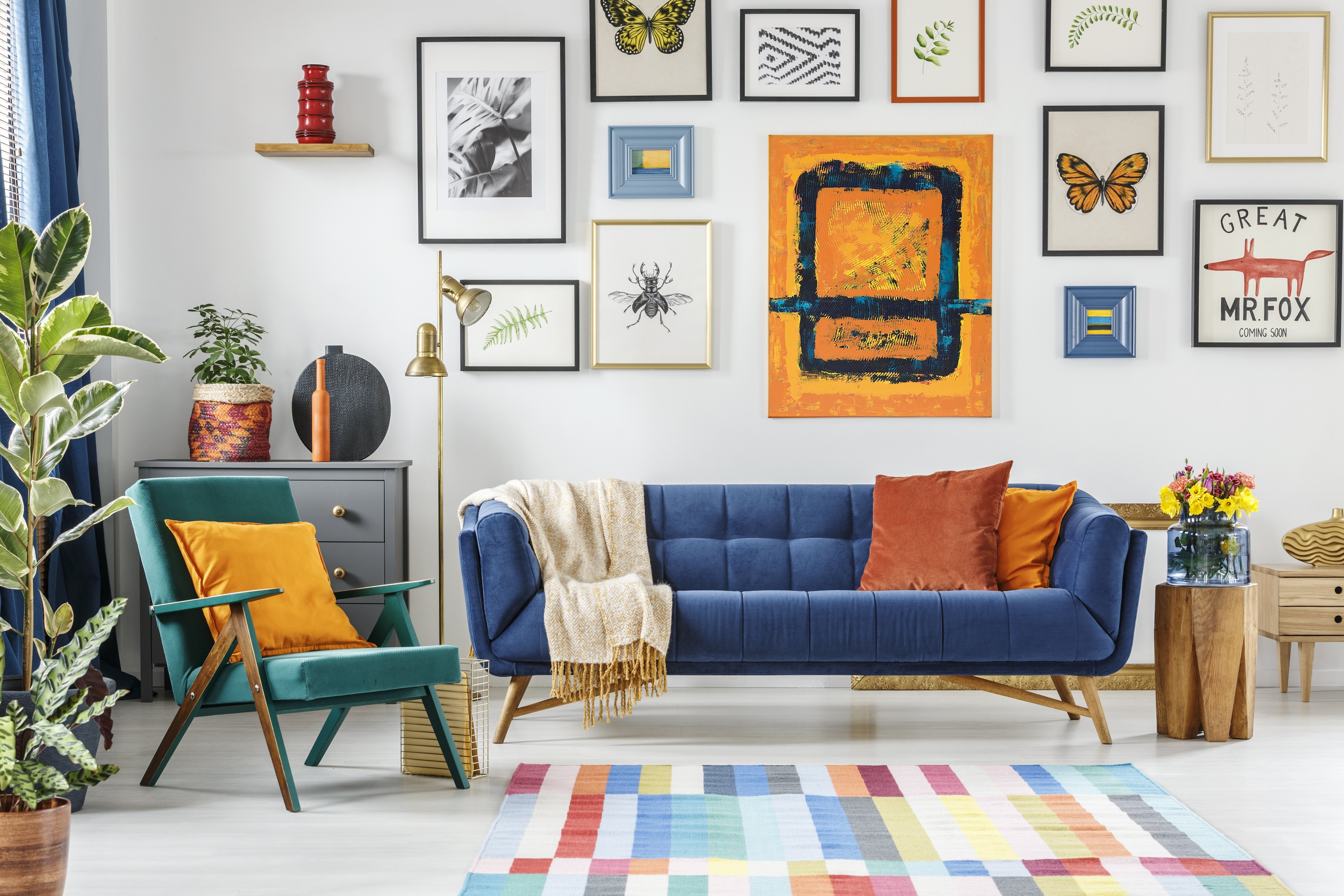 A living room with a blue couch, a green chair, and a colorful rug.