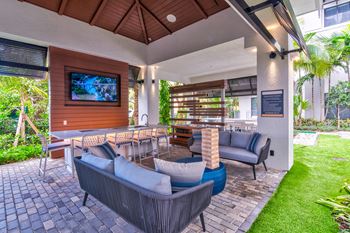 A patio with a couch, chairs, and a television at Mayla Pompano, Pompano Beach, Florida