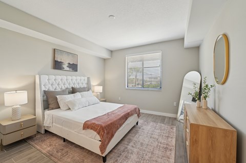 A bedroom with a large bed and a wooden dresser.