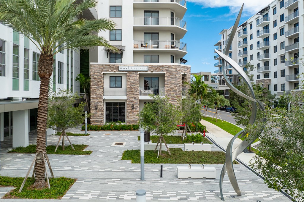 A modern building with a courtyard and palm trees at Mayla Pompano, Pompano Beach