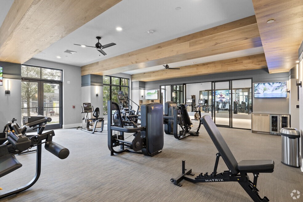 a gym with weights and cardio machines and glass doors at Mayla Pompano, Pompano Beach