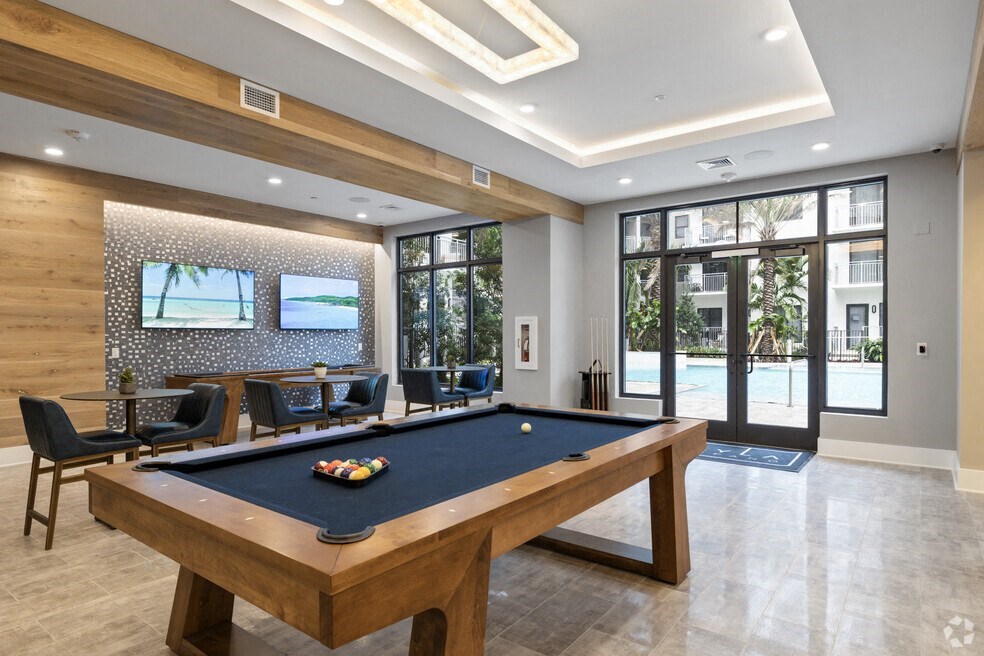 a pool table in a room with a tv and chairs at Mayla Pompano, Pompano Beach, FL