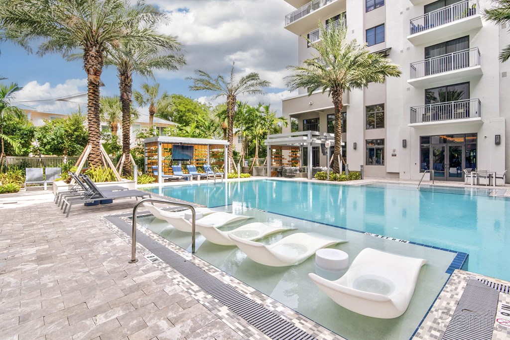 A pool with sun loungers and a building at Mayla Pompano, Pompano Beach