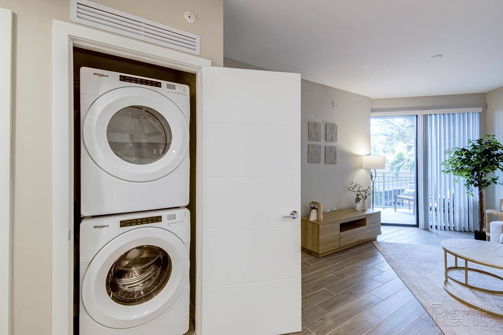 A white washing machine is in a cabinet in a room with a wooden floor at Mayla Pompano, Pompano Beach, 33062