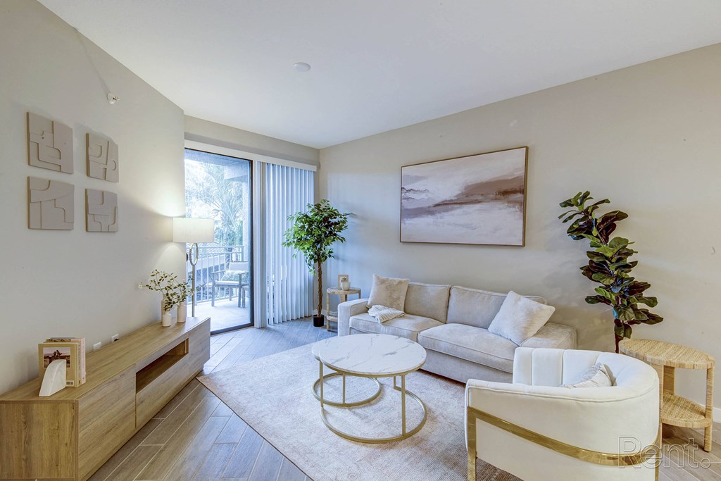A living room with a white couch, a coffee table, and a potted plant at Mayla Pompano, Pompano Beach, Florida
